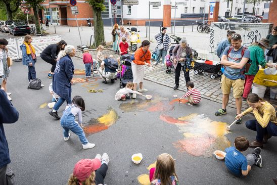 Photo: Many children play and paint on a cordoned-off street.