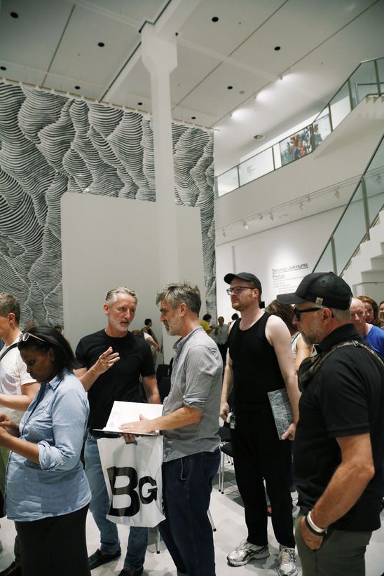 Some people are queuing up while holding exhibition catalogues in their hands.