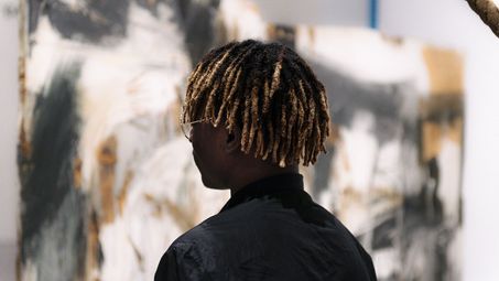 Foto: Besucher*in vor einem Kunstwerk, das Exponat betrachtend.