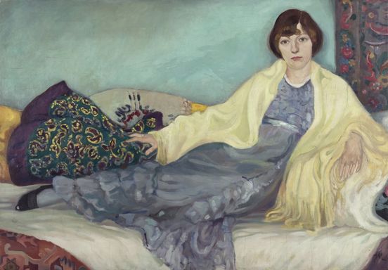 Gemälde einer Frau, die auf einem Sofa sitzt. Sie trägt ein fließendes blaues Kleid und ein gelbes Tuch über den Schultern. Der Hintergrund ist türkisfarben, und um sie herum liegen gemusterte Kissen und Teppiche.