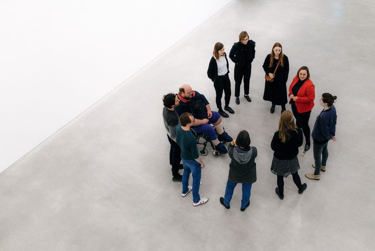 Foto: Bei einer Führung sind Menschen mit und ohne Rollstuhl in einem Kreis versammelt.