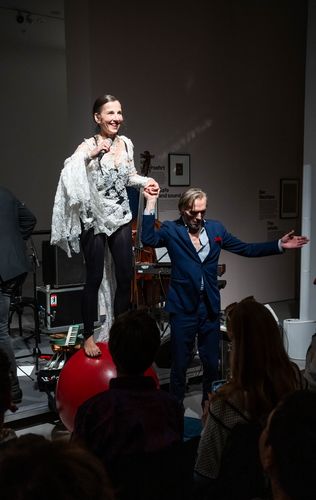 Meret Becker Foto: Meret Becker singt auf einem roten Gymnastik-Ball, während sie von einer weiteren Person gestützt wird.
