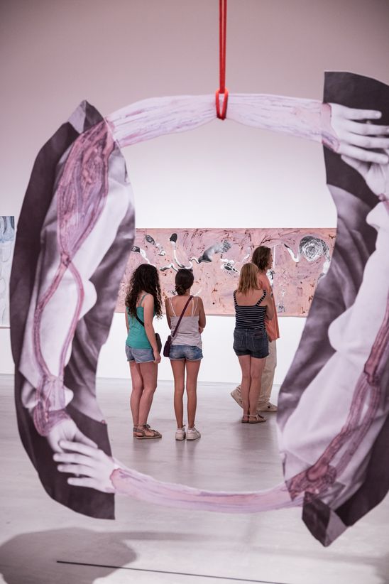 Photo: Some people stand between a hanging sculpture and a painting by Özlem Altın.