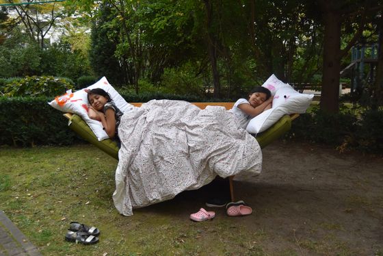 Foto: Kinder liegen in einem selbstgebauten Bett im Wald.