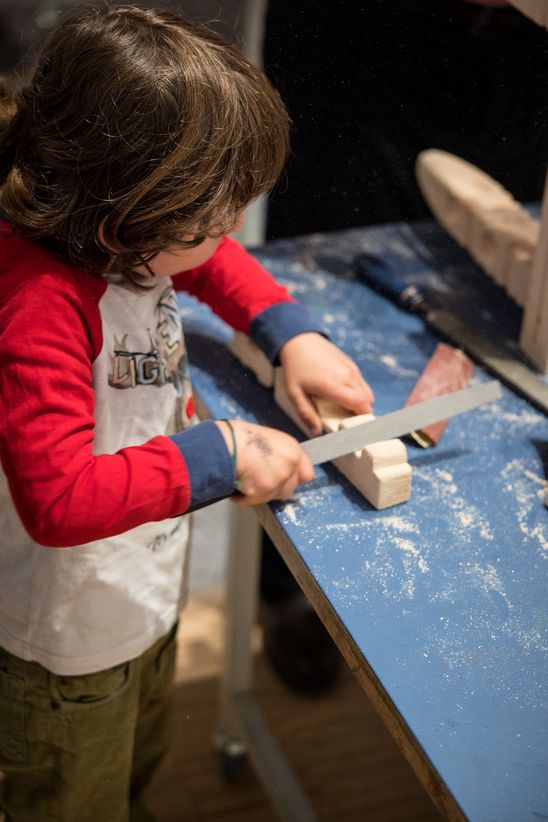 Photo: Close-up of a child sanding a piece of wood.