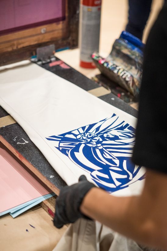 Photo: Close-up of a gloved hand holding a piece of paper printed with blue ink.