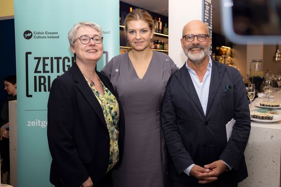Foto: Drei Personen stehen vor einem Banner, auf dem „Zeitgeist Irland“ steht und lachen in die Kamera.