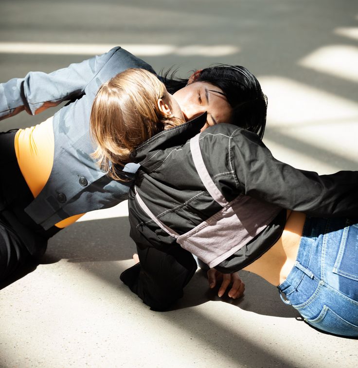 Photo: Two people are lying opposite each other on the floor in the sun. Their mouths are touching.