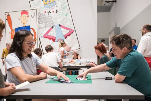 Impressions of the Long Night of Museums 2024 Photo: Some people are sitting at tables in the project room of the Berlinische Galerie, playing card games, doing handicrafts and chatting.