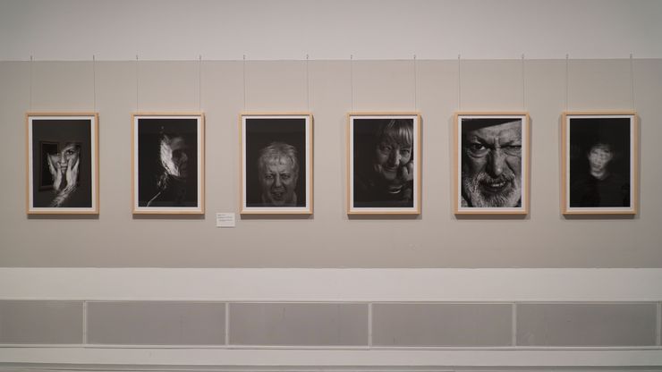 Foto: Sechs Foto-Porträts an einer Wand.