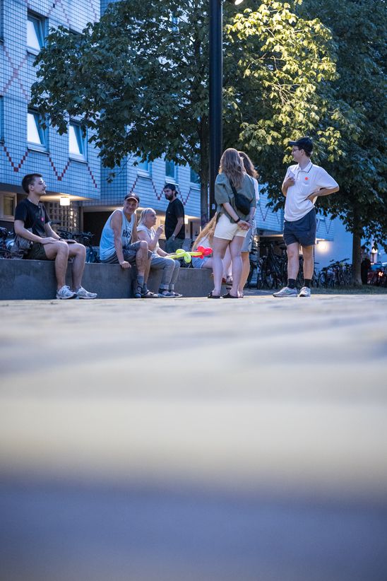 Photo: Some people are sitting and standing outside next to a tree.