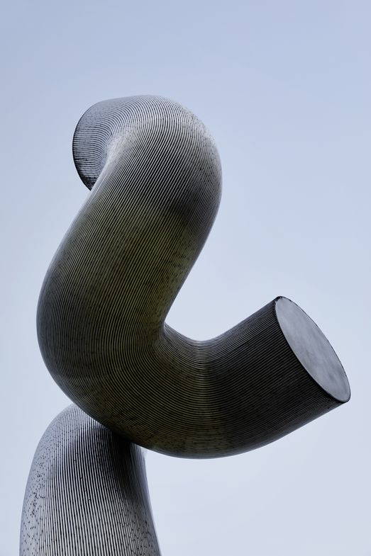 Foto: Teil einer Skulptur aus silbernem Metall vor blauem Himmel