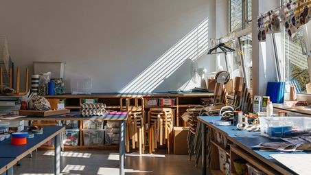 Foto: Ein Werkstattraum mit Arbeitstischen, Stühlen und Materialien.