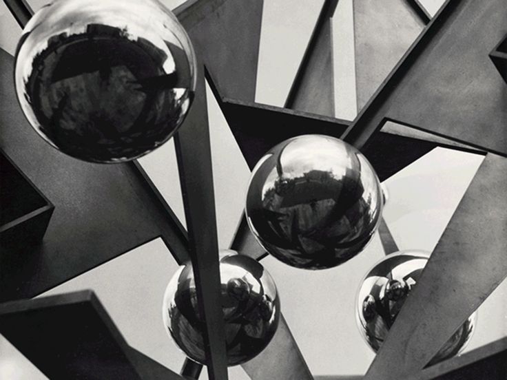 GIF: Kurze Aneinanderreihung von drei Fotos. Das erste Foto ist ein schwarz-weiß-Foto und zeigt im Ausschnitt eine Metall- und Stahlskulptur mit spiegelnden Kugeln und weiteren Formen. Das zweite Bild zeigt ein Modell eines bewachsenen Gebäudes, dessen beide Hälften jeweils eine Jahreszeit, Sommer und Winter, darstellen. Das dritte Bild ist eine Collage. Auf schwarz-weißem Druck sind Gebäudeteile des Kotti (Kottbusser Tor) und Fliesen zu sehen. Der Vordergrund zeigt eine leuchtend gelbe Kleberolle mit der Aufschrift „Allgemeingut / Common Property“ 