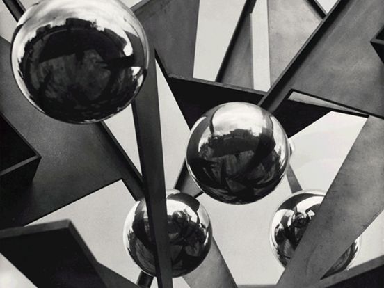 GIF: Kurze Aneinanderreihung von drei Fotos. Das erste Foto ist ein schwarz-weiß-Foto und zeigt im Ausschnitt eine Metall- und Stahlskulptur mit spiegelnden Kugeln und weiteren Formen. Das zweite Bild zeigt ein Modell eines bewachsenen Gebäudes, dessen beide Hälften jeweils eine Jahreszeit, Sommer und Winter, darstellen. Das dritte Bild ist eine Collage. Auf schwarz-weißem Druck sind Gebäudeteile des Kotti (Kottbusser Tor) und Fliesen zu sehen. Der Vordergrund zeigt eine leuchtend gelbe Kleberolle mit der Aufschrift „Allgemeingut / Common Property“ 