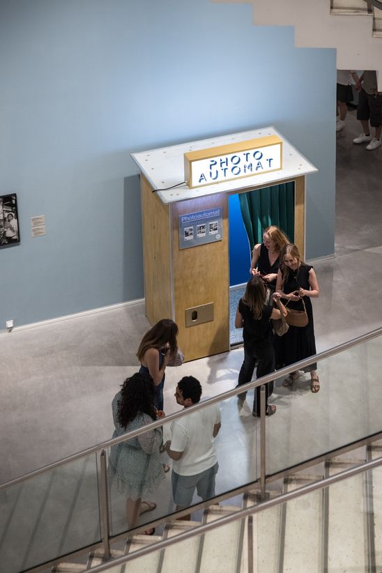 Photo: Some people stand in front of a wooden photo booth in the exhibition room.