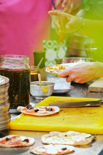 Eindrücke der Veranstaltung „Slices & Spices – Über Essen & Gemeinschaft“ im Rahmen des BG Sommer Festival Foto: Nahaufnahme von zwei Händen, die gerade Pizza zubereiten.
