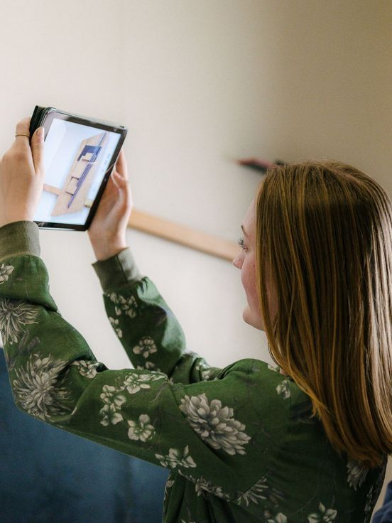 Photo: Two young visitors hold a tablet. It shows a photograph of a work of art.