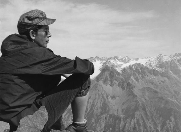 Schwarz-weiß-Foto: Brigitte Meier-Denninghoff sitzt in Wander-Montur vor einem Bergpanorama.