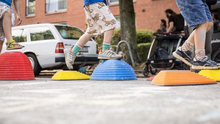 Kinderbeine die auf der Spielstraße laufen