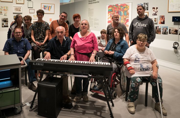 Das Bild zeigt eine Gruppe von Menschen, die in der Berlinischen Galerie um ein Keyboard herum sitzen und stehen. Sie sind Teil der Kunstwerkstatt der Lebenshilfe Kreuzberg.