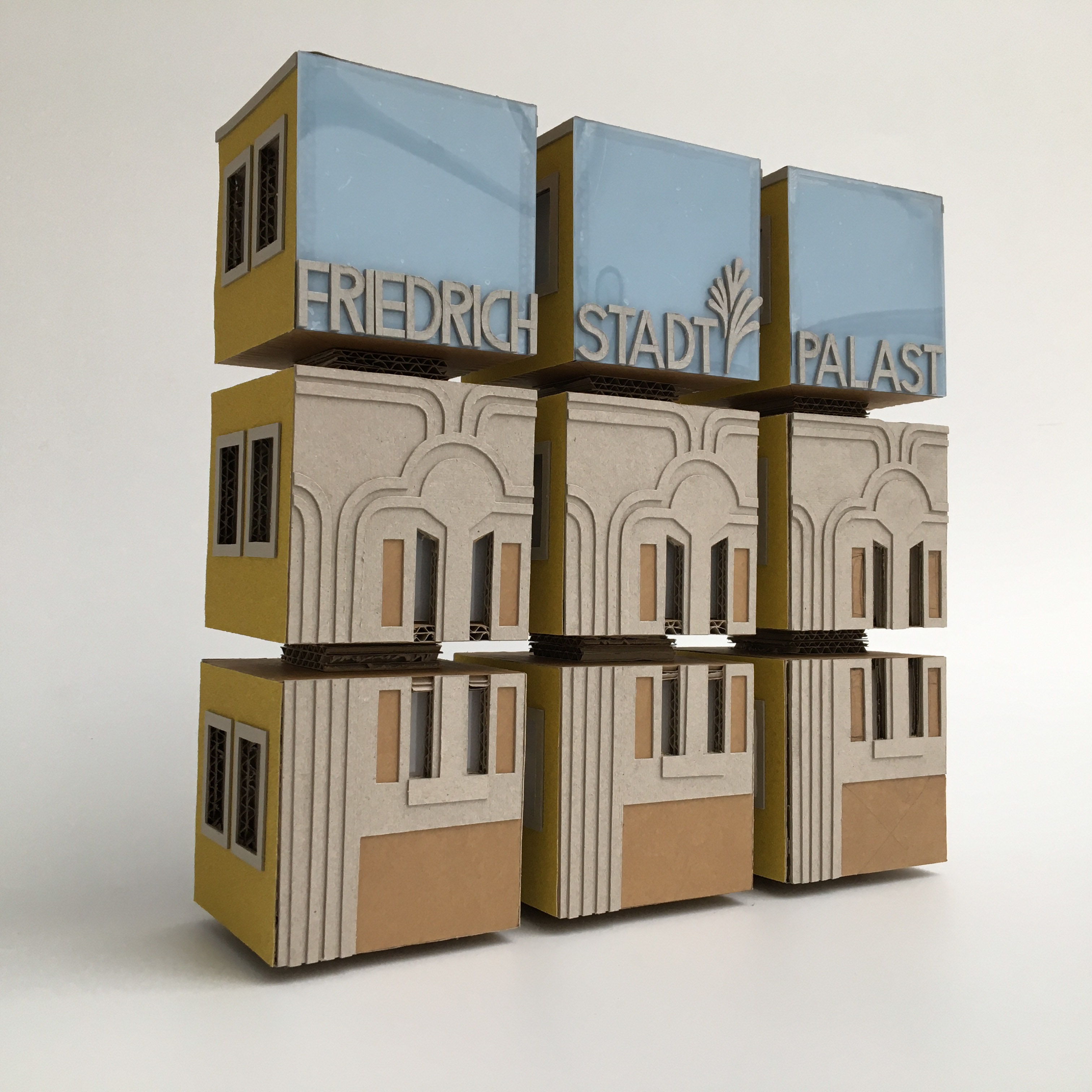 Tastobjekt aus 9 Papp-Würfeln, die einen Quader bilden. Die Fassade eines Hauses und die Worte "Friedrichstadt-Palast" sind taktil hervorgehoben.