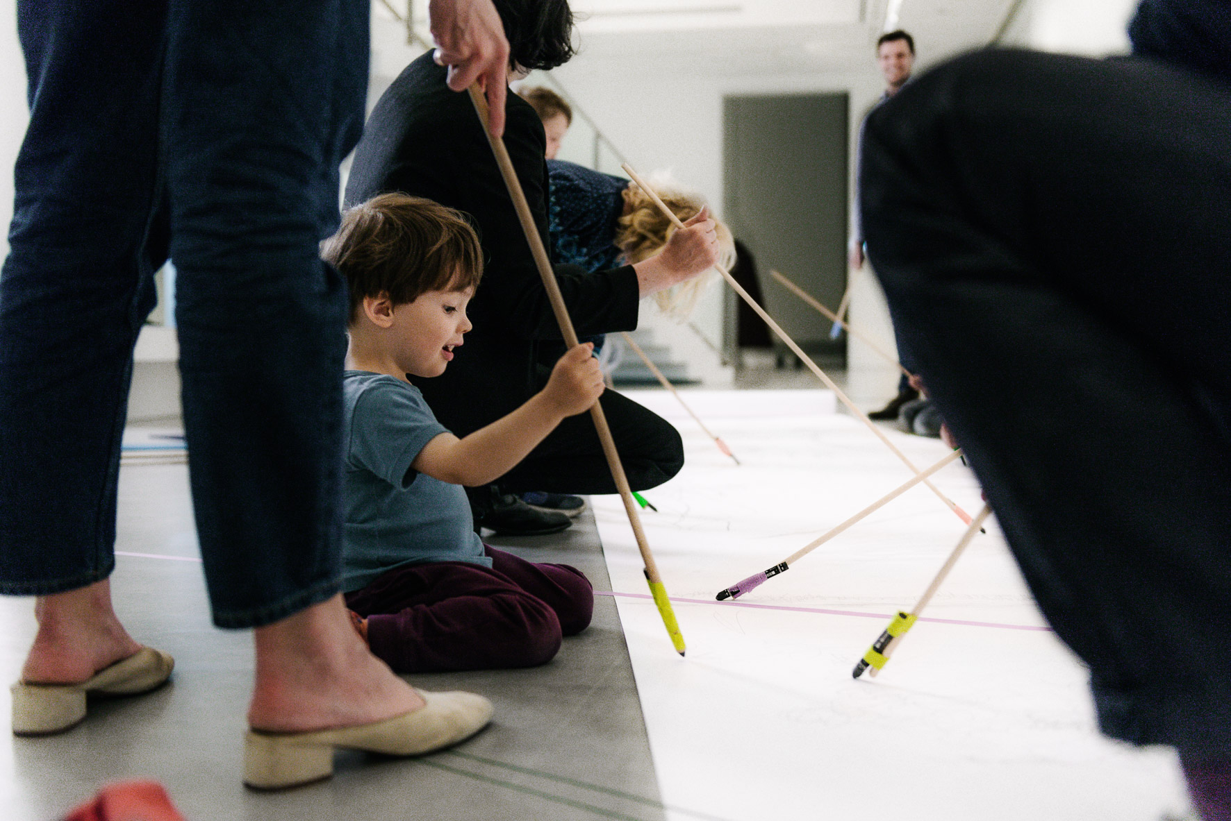 Foto: Ein Kind und mehrere Erwachsene malen gemeinsam am Boden.